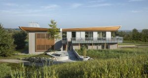 Conciencia de la naturaleza, eficiencia energética, orientación hacia el futuro. Estos tres temas dominaron el proceso de diseño de esta casa Baufritz en un entorno precioso de prados y grandes árboles. Es una casa para una pareja de jubilados que deseaban convivir con la naturaleza, un deseo que se cumplió por una parte con grandes ventanales de triple acristalamiento que dejan que el paisaje entre y forme parte de su vida cotidiana, y por otra parte con una selección exquisita de materiales naturales para el interior de la casa. Además, es una casa que parece conciliar a la perfección la tradición con la modernidad, un hogar que respira tranquilidad y buenas ondas.